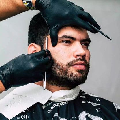 Barber cutting a customer's hair with clippers and wear a nitrile glove against a neutral background
