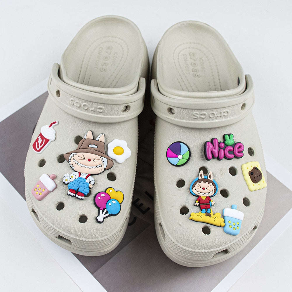 Beige clogs with colorful decorative labubu shoe charms pins on a white background