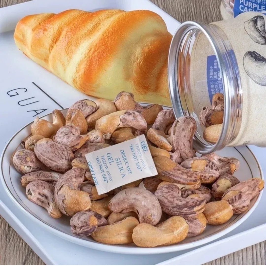 Cashews in a bowl with a jar of cashews and a croissant on a white plate.