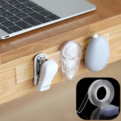 White cable management clips sticked by nano tape on a wooden surface with a laptop in the background