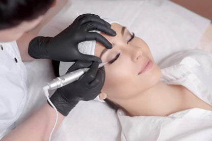 Person receiving a facial treatment wearing a pair of black nitrile gloves with a device from a professional in a clinical setting.